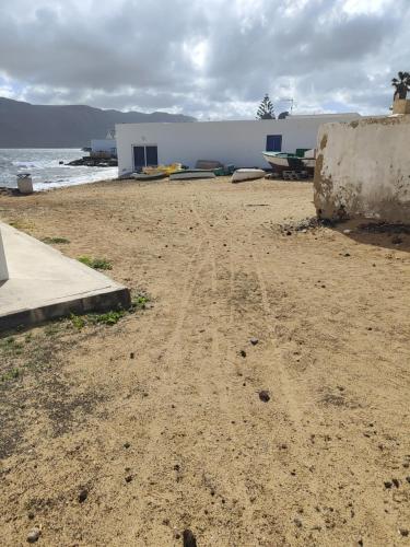 a sandy beach with a building and the ocean at Loft la Caletilla in Caleta de Sebo