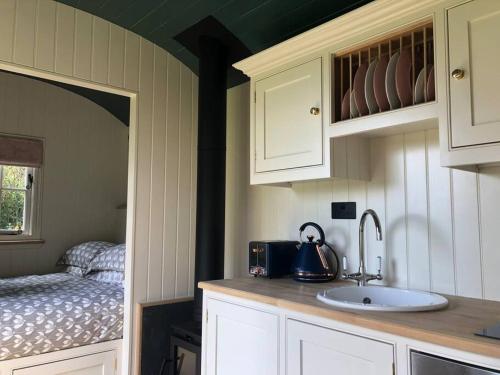 una cocina con fregadero y una cama en una habitación en The Old Vicarage Shepherd's Hut, en Stroud