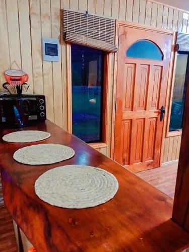 a wooden table with four plates on it with a door at Tu cabaña en paraíso termal in Liquiñe