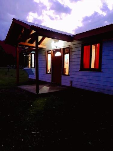 Liquiñe的住宿－Tu cabaña en paraíso termal，蓝色的房子,有红色的门和窗户