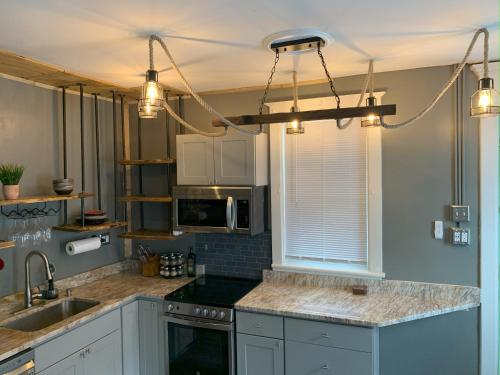 een keuken met witte kasten, een wastafel en verlichting bij Rustic Riverfront Retreat in Harrisburg