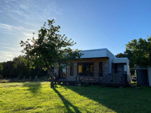 een klein huis in een veld met een boom bij Cabañas Nalhuitad in Molina