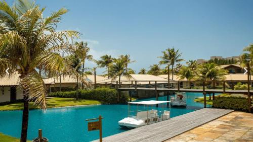 a resort swimming pool with a dock and palm trees at Dom Pedro Laguna Beach Resort & Golf in Fortaleza