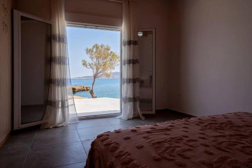 a bedroom with a large window with a view of the ocean at Poseidon House in Pollonia
