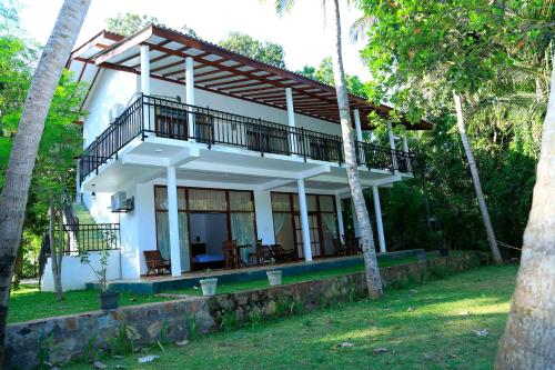 uma casa branca com uma varanda em cima em River Edge Yala em Tissamaharama