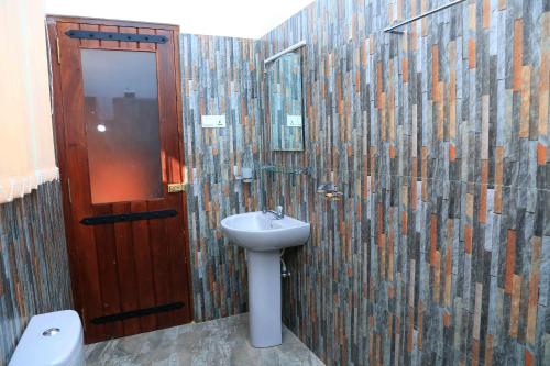 a bathroom with a sink and a wooden door at River Edge Yala in Tissamaharama