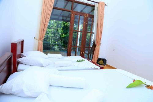 two beds in a room with a window at River Edge Yala in Tissamaharama