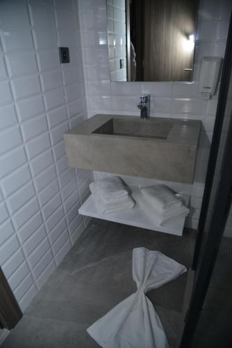 baño con lavabo y una pila de toallas en Privilège Oasis Hôtel en Casablanca