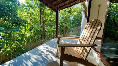 a rocking chair on a porch with trees at Loft novo em Morro de São Paulo in Morro de São Paulo