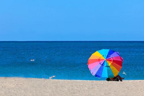 a person sitting on the beach under a colorful umbrella at Villa Tranquility-Waterfront-Punta Gorda, FL in Punta Gorda
