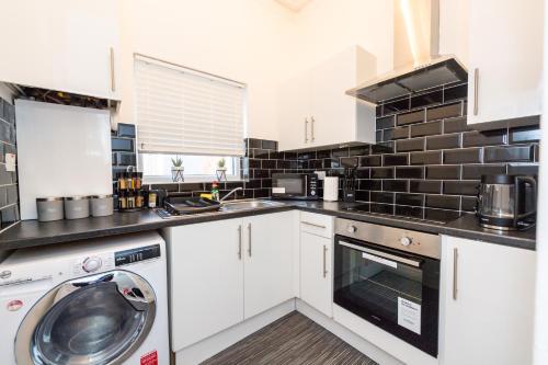 a kitchen with white cabinets and a washer at Benoît Apartments in Manchester