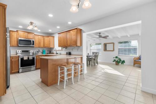 a kitchen with wooden cabinets and a kitchen island with bar stools at Family Retreat near Beach, Downtown and PGA in Palm Beach Gardens