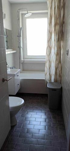 baño con aseo y lavabo y ventana en Apartament nad morzem Sopot, en Sopot