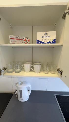 a kitchen with a shelf with bowls on it at Apartment am Zollverein -WiFi - Parking for free in Essen