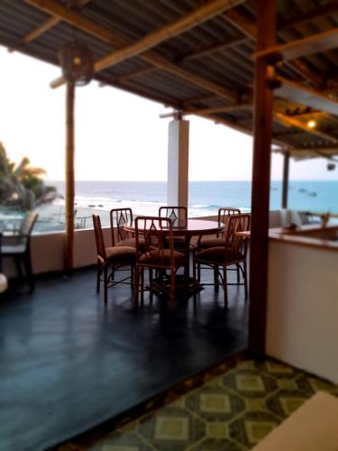 un comedor con mesa y sillas y el océano en Hospedaje Casa Mercedes Beach, en Canoas de Punta Sal