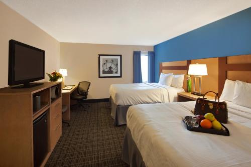 a hotel room with two beds and a flat screen tv at Canadas Best Value Inn Toronto in Toronto