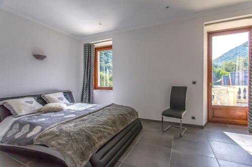 a bedroom with a bed and a chair and a window at Domaine au cœur des 3 vallées in Moutiers