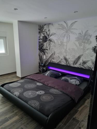 Ce lit se trouve dans un dortoir doté d'un mur avec des palmiers. dans l'établissement La belle étoile, 