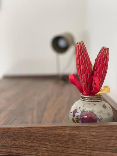 a vase with red flowers in it sitting on a table at La Remise-Gîte de charme 7 personnes avec jacuzzi in Saint-André-de-Sangonis