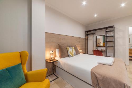 ein Schlafzimmer mit einem Bett und einem gelben Stuhl in der Unterkunft AlohaMundi Montesión in Sevilla