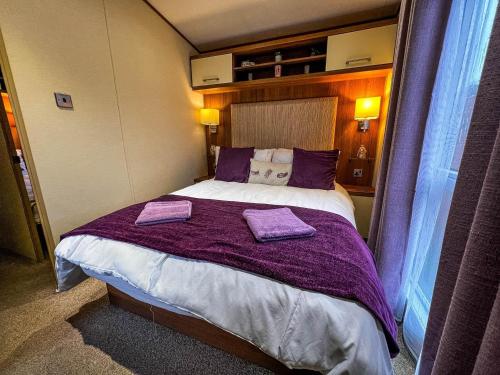1 dormitorio con 1 cama grande con mantas moradas en Superb Lodge In Rural Norfolk Near Norwich, With Lake Views Fishing Ref 16018h, en Cawston