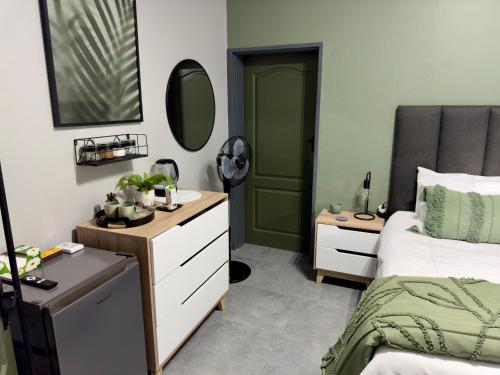Schlafzimmer mit einem Bett, einer Kommode und einem Spiegel in der Unterkunft Wild Fig Rest Guest House in Polokwane