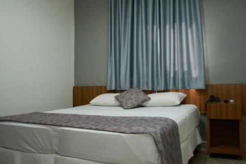 a bedroom with a large bed with a window at BOMBONATO HOTEL - Fácil Acesso ao Aeroporto e parque de Exposições ABCZ in Uberaba
