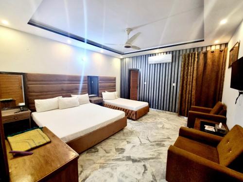 a bedroom with a bed and a desk and a chair at Pakeeza One Hotel in Lahore