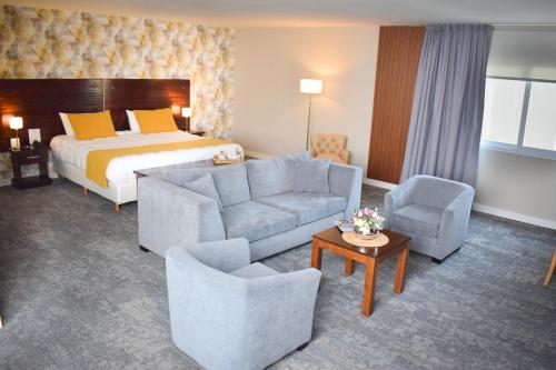 a hotel room with a bed and a couch and chairs at Howard Johnson Plaza & Convention Center Spa La Plata in La Plata