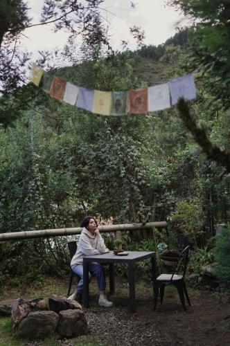 a woman sitting at a table in a garden at Cabañas de montaña en Chía - Satorinatural in Chía