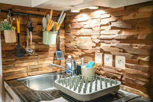 - une cuisine avec un évier et un mur en bois dans l'établissement Cabana & Merci Annecy - Parking et Proche du Lac, à Annecy