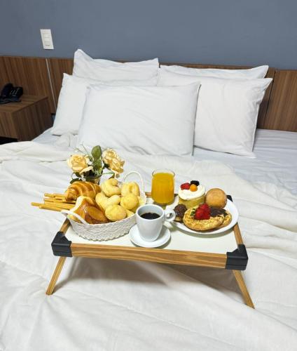 a tray of breakfast foods on a bed at BOMBONATO HOTEL - Fácil Acesso ao Aeroporto e parque de Exposições ABCZ in Uberaba
