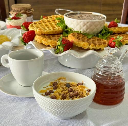 a table with a breakfast of cereal and waffles and strawberries at BOMBONATO HOTEL - Fácil Acesso ao Aeroporto e parque de Exposições ABCZ in Uberaba