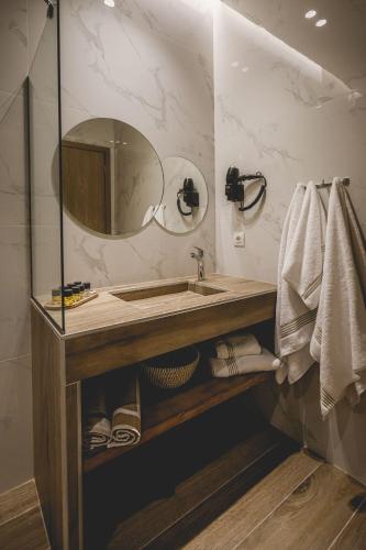 a bathroom with a sink and a mirror and towels at Naias Nemeia Luxury Rooms in Neméa