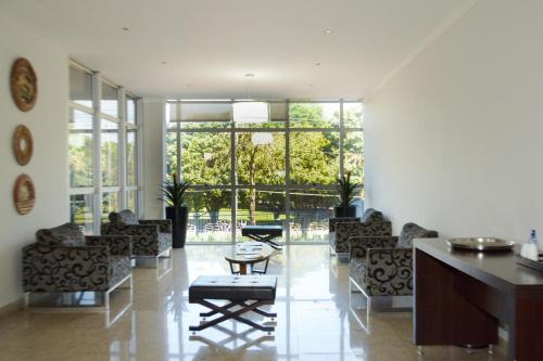 un soggiorno con sedie, tavolo e finestre di BOMBONATO PALACE HOTEL a Uberaba