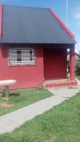 une maison rouge avec une table de pique-nique devant elle dans l'établissement La Morada, à San Roque