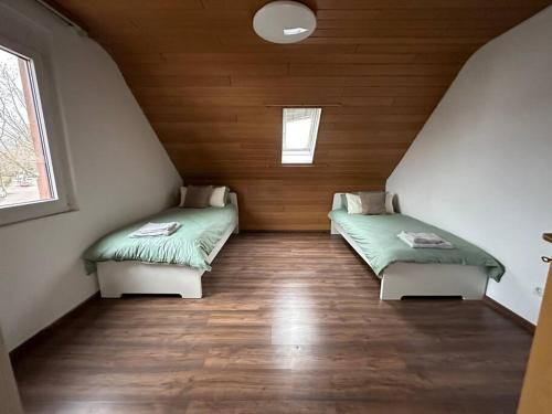 two beds in a room with wooden walls and wood floors at Ferienwohnung Malin in Ludwigshafen am Rhein