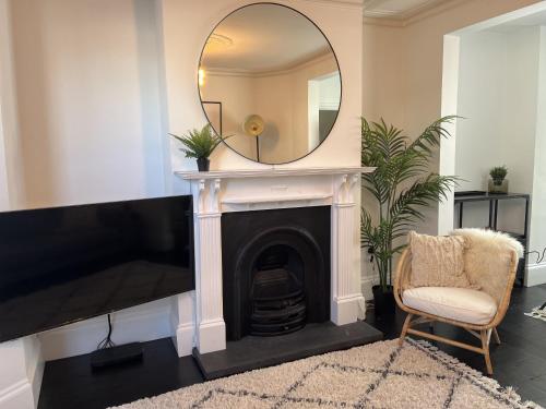 a living room with a fireplace and a mirror at Restored Victorian Home with Private Garden in Bristol