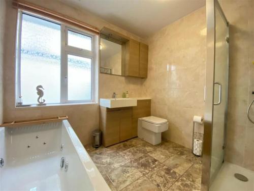 a bathroom with a tub and a toilet and a window at Brixham View House in Torquay