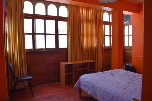 um quarto com paredes cor de laranja, uma cama e janelas em Casa a 3 cuadras de la plaza de armas Huamanga em Ayacucho