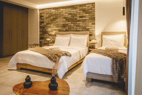 a bedroom with two beds and a brick wall at Naias Nemeia Luxury Rooms in Neméa