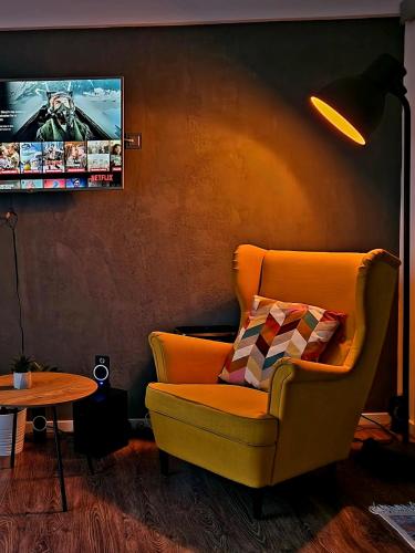 a living room with a yellow chair and a tv at Self Check-IN Free Parking Near Metro Stations and BUS WestSide Studio S6 in Bucharest