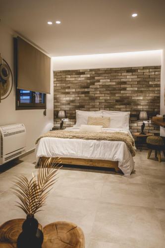 a bedroom with a large bed and a brick wall at Naias Nemeia Luxury Rooms in Neméa