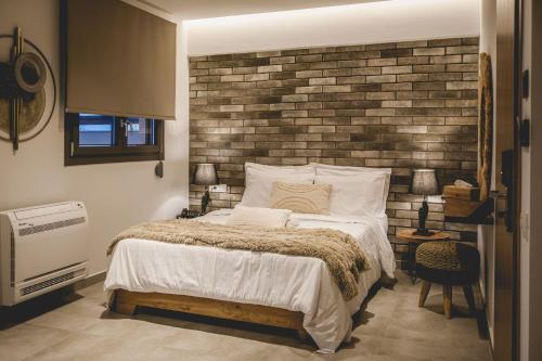 a bedroom with a bed and a brick wall at Naias Nemeia Luxury Rooms in Neméa