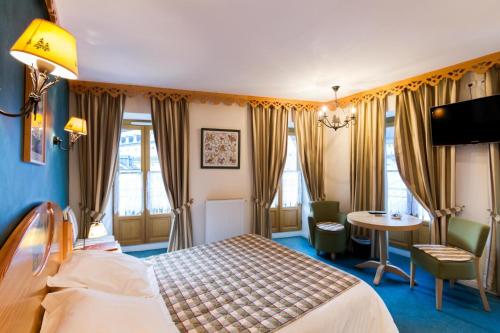 コトレにあるオテル ル ボワ ジョリのベッドとテーブルが備わるホテルルームです。