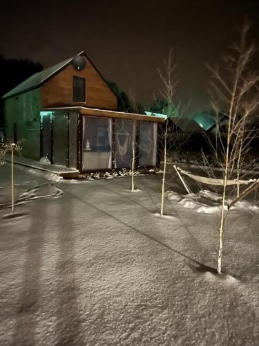 una casa de noche con árboles delante de ella en Domki trzy jeziora z zewnętrznym SPA - sauna, balia do schładzania i jacuzzi, en Małe Swornigacie