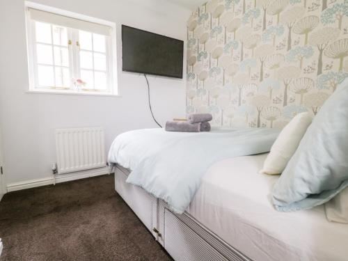 a bedroom with a white bed and a window at Swallow Cottage in Herne Bay