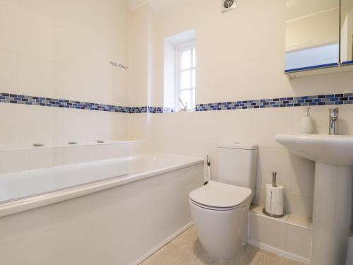 a white bathroom with a toilet and a sink at Swallow Cottage in Herne Bay