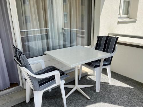 einen weißen Tisch und zwei Stühle vor einem Fenster in der Unterkunft Landwasser in Davos