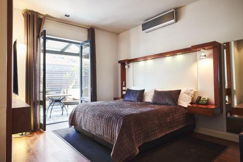 a bedroom with a large bed and a balcony at Hotel on the Promenade in Cape Town